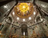 Intérieur de la Chapelle des Médicis, dôme orné de fresques dorées et de peintures religieuses, murs décorés de marbre et de sculptures.