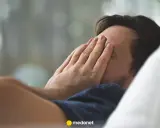 Mężczyzna zasłania twarz dłońmi, czując **brain fog**.