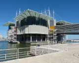 Das moderne Aquarium Lissabon ragt mit seinen Glasdächern und Betonstrukturen über dem Wasser auf.