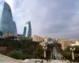 Płomienne wieże Flame Towers w Baku, które warto zobaczyć, górują nad miastem. W tle widać panoramę miasta i zielone drzewa.