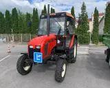 Czerwony traktor Zetor z tabliczką "L" na masce, gotowy do egzaminu na prawo jazdy na traktor.