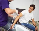 Fizjoterapeuta stosuje terapię falą uderzeniową na ramieniu pacjenta, aby złagodzić ból i przyspieszyć regenerację.