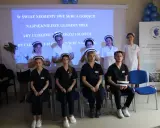 Uczelnia Medyczna im. Marii Skłodowskiej-Curie w Warszawie: studenci w strojach medycznych, z hasłem na ekranie.