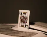 Król pik znaczenie. Pojedyncza karta, król pik, stoi na stosie kart.