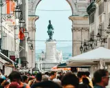 Menschenmenge auf der Rua Augusta in Lissabon mit Reiterstatue und Triumphbogen im Hintergrund.