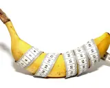 Żółty banan owinięty miarką krawiecką, pokazujący, jak wygląda penis.
