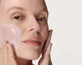 Donna applica delicatamente crema viso con le dita, un gesto semplice per prendersi cura della pelle.