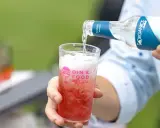 Tonic water wird in ein Glas mit rotem Getränk gegossen. Perfekt, um den Sommerdrink zu mischen.
