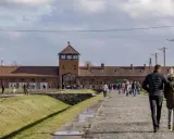 Spacer po terenie byłego obozu Auschwitz. Para idzie w stronę bramy z wieżą.