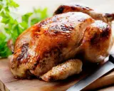Un appétissant poulet rôti sur une planche en bois, prêt à être dégusté. Quel vin avec poulet rôti ? Un blanc fruité ou un rouge léger serait parfait.
