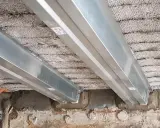 Vigas metálicas instaladas para como reforzar una viga de madera dañada por el fuego. Se observa el soporte de las nuevas vigas sobre la estructura existente.