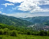 Zielone wzgórza Karpat na Ukrainie, z miasteczkiem w dolinie i rzeką.