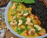 Ein cremiges Beluga Linsen Curry mit Cashewkernen und frischer Petersilie, daneben eine Portion schwarzer Beluga Linsen.