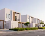 Frente fachadas de casas modernas con líneas limpias y detalles en madera. Un camino de adoquines y césped verde adornan el exterior.