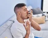 Mężczyzna używa inhalatora, szukając ulgi w objawach astmy. Leki na astmę bez recepty mogą pomóc w łagodzeniu napadów.