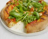 En närbild av en pizza med ruccola och basilika. Perfekt för ett enkelt pizzasås recept.