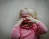Małe dziecko uderza głową, płacząc. Może to być sygnał, że potrzebuje pomocy psycholog.