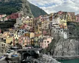 Case colorate aggrappate alla roccia, un paesaggio da cartolina. Cinque blues per la banda Monterossi, un'armonia di tinte vivaci che abbraccia il mare.