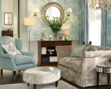 Przytulne mieszkanie w stylu angielskim z błękitnymi fotelami, beżową kanapą, ozdobną tapetą i kryształowym żyrandolem.