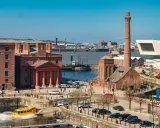 Albert Dock in der Liverpool Stadt, mit einem gelben Amphibienfahrzeug im Wasser und einem hohen Schornstein.