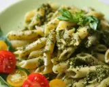 Penne z pesto i pomidorkami koktajlowymi. Pyszny obiad bez mięsa, udekorowany listkami bazylii.