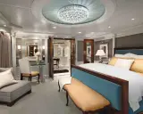 Lussuosa suite crociera con letto king-size, divanetto, lampadario di cristallo e vista su un corridoio elegante.