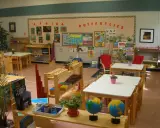 Klasa przygotowana zgodnie z metodą Montessori: globusy, książki o Afryce i motylach, materiały edukacyjne na półkach.