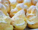 Une assiette de choux à la crème, saupoudrés de sucre glace. Ces petites merveilles de chou patisserie sont prêtes à être dégustées.