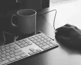 Ręka programisty nad klawiaturą, kubek kawy i myszka. Czas na programowanie aplikacji.