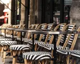 Terrasses parisiennes avec chaises et tabourets rayés, prêts à accueillir les gourmands pour déguster les spécialités paris.
