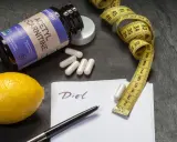 Flasche L-Carnitin, Kapseln, Zitrone, Maßband und Notiz "Diet". Mögliche l-carnitin nebenwirkungen im Blick.