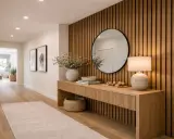 Entrada moderna con pared de listones de madera, consola, espejo redondo y lámpara. Inspiración para como poner listones de madera en la pared.