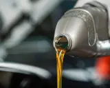 Huile moteur dorée versée d'une bouteille, illustrant la viscosité.