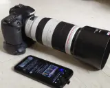 Canon 80D con obiettivo 100-400mm, pronto per una recensione. Sullo smartphone, un tweet su politica.