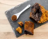 Morceaux de chaga brut et en poudre sur une ardoise, évoquant les nombreux chaga bienfaits pour la santé.