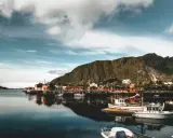 Malowniczy norweski port z czerwonymi domkami i łodziami. Czy do Norwegii trzeba mieć paszport? Sprawdź przed podróżą!