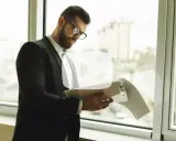 Hombre con gafas revisa documentos. Explica qué es un aval bancario para alquiler, una garantía para el arrendador.