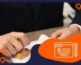 Persona con traje sella un documento, quizás para tramitar un carnet conducir. Icono de blog al lado.