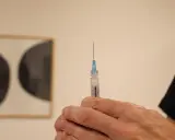 En hand håller en spruta med en droppe vaccin redo för injektion. Kanske en del av vaccin Singapore-programmet.
