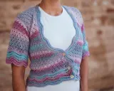 Chaqueta de crochet con rayas degradadas en tonos pastel y delicados puntos calados. Tres botones de madera cierran la prenda.