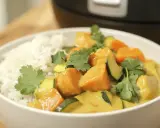 Un bol de riz blanc servi avec un curry de légumes coloré, garni de coriandre fraîche.