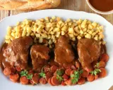 Delicioso jarrete de ternera estofado en salsa, acompañado de patatas fritas y zanahorias.