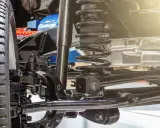Primer plano de la suspensión de un coche, mostrando el amortiguador, muelle y brazos de control. Así es que es la suspensión de un coche.