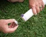 Przygotowanie do klejenia rur PVC. Ręka trzyma puszkę z klejem, a druga ręka przygotowuje rurę.