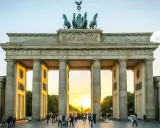 Brandenburger Tor i Berlin, en ikonisk sevärdhet som visar vad man ska se i Berlin. Solnedgången lyser upp monumentet och folklivet.