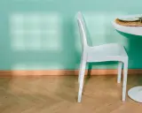 Un battiscopa in legno chiaro completa l'arredamento di una stanza con parete verde acqua, sedia bianca e tavolo.