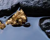 Oro grezzo, scintillante tra rocce scure e acqua limpida. Un'immagine che evoca il mistero di come nasce l'oro.