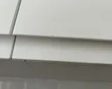 Detalle de un mueble lacado blanco con pequeños arañazos, listo para reparar.