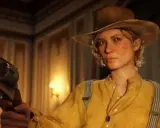 Sadie Adler w kapeluszu i żółtej koszuli trzyma rewolwer, gotowa do akcji.