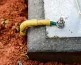 Connexion de la prise de terre maison à une structure métallique, assurant la sécurité électrique. Le câble jaune est relié à une cosse verte, fixée par un boulon.